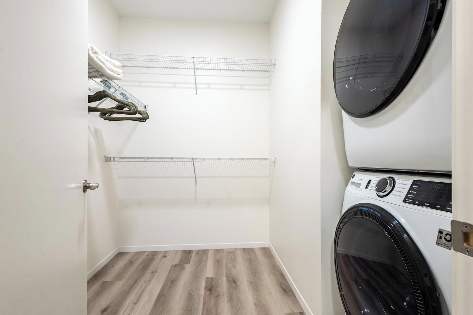 Une buanderie équipée d’un lave-linge, d’un sèche-linge et d’un étendoir métallique.