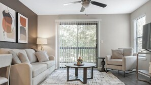Una sala de estar con sofá, sillón, una mesa de centro redonda y ventilador de techo.