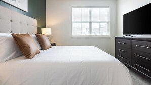 A hotel room with a bed, a television, a window with blinds, and a dresser. - Landing | Chic 1BD in Steelpointe Harbor (Bridgeport)