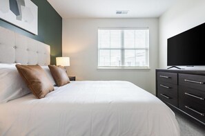A hotel room with a bed, a television, a window with blinds, and a dresser. - Landing | Chic 1BD in Steelpointe Harbor (Bridgeport)