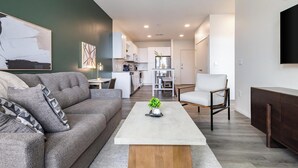 A modern living room with a grey sofa, a coffee table, and a TV mounted on the wall. - Landing | Chic 1BD in Steelpointe Harbor (Bridgeport)