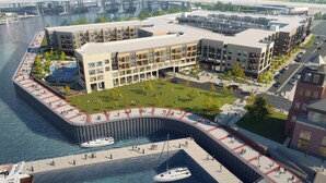 A waterfront building with multiple floors, a central courtyard, and a dock area with boats. - Landing | Chic 1BD in Steelpointe Harbor (Bridgeport)