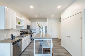 A modern kitchen with white cabinetry, stainless steel appliances, and a central island with seating.