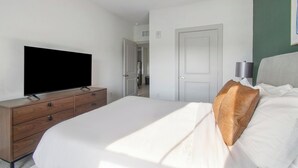 Ein Hotelzimmer mit einem Bett, einem Fernseher auf einer Holzkommode, einer Tür und einer Wandleuchte.