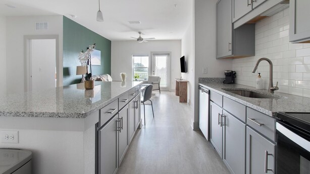 Eine moderne Küche mit Granit-Arbeitsplatten, Edelstahlgeräten und Blick zum Wohnbereich.