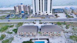 Een hotel aan het strand met meerdere gebouwen, een parkeerplaats en een zwembad.