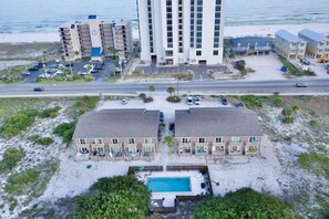 Ein Hotel direkt am Strand mit mehreren Gebäuden, einem Parkplatz und einem Schwimmbad.