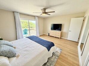 Une chambre à coucher avec un lit, un ventilateur de plafond, une télévision et une porte coulissante.