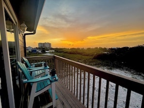 A balcony with a view of a sunset over a beach and buildings. - The Current at Lost Key (Pensacola)