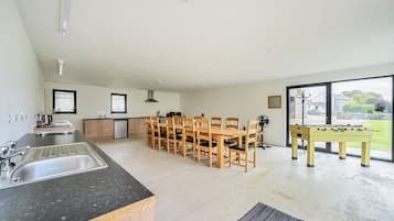 A modern kitchen with a dining area, a foosball table, and a view of the outdoors.
