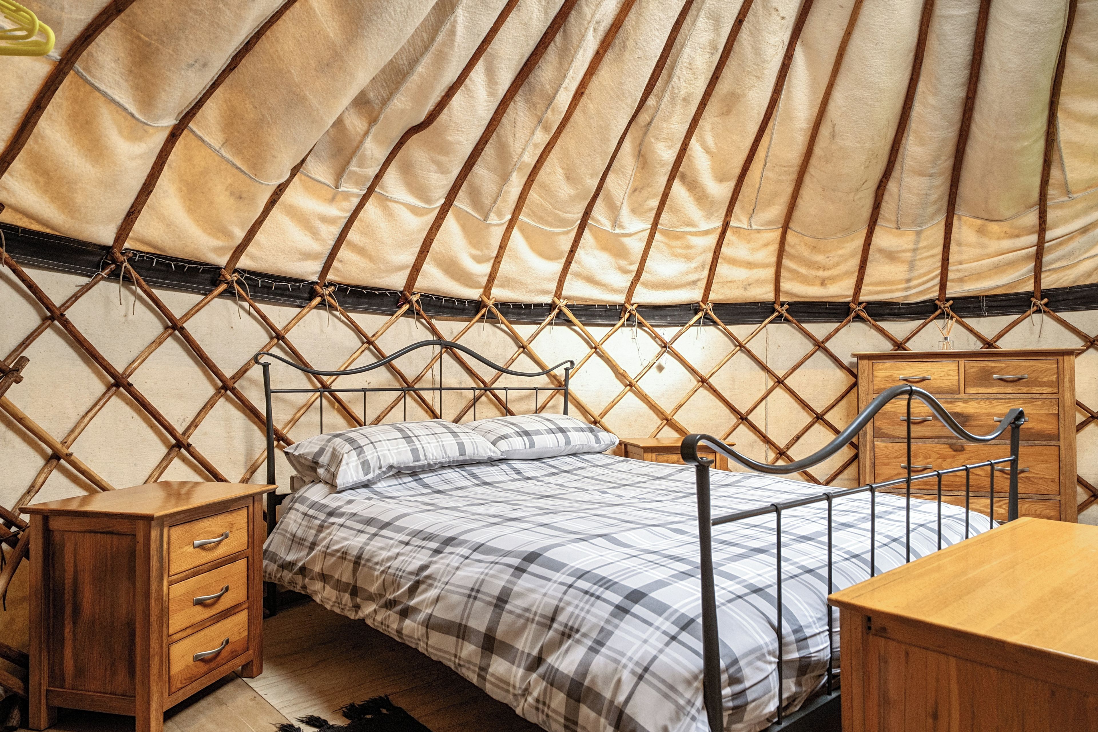 A room with a bed, wooden furniture, and a large tent-like structure.