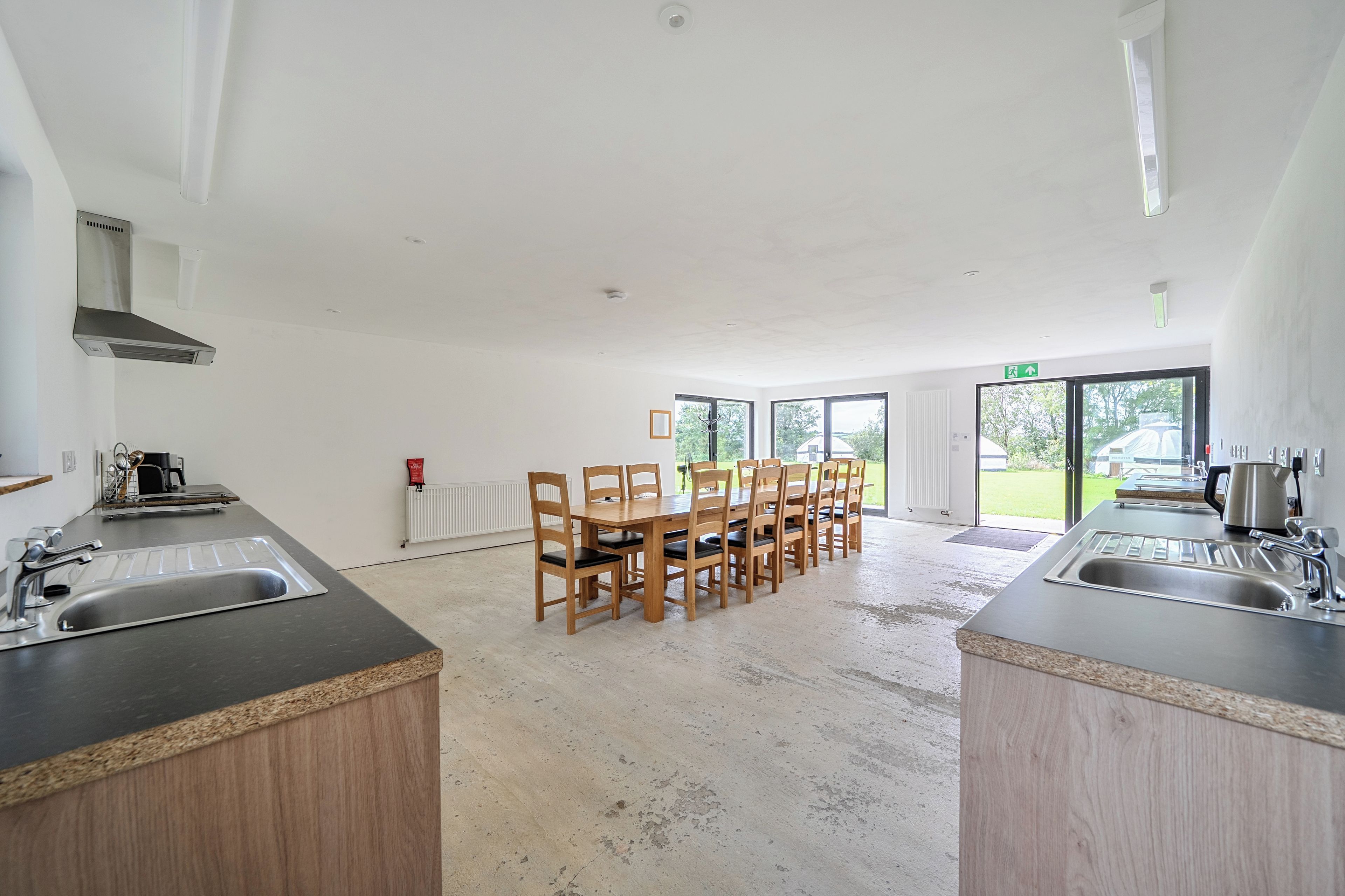 A modern kitchen with a central island, wooden chairs, and a large window providing a view of the outdoors.