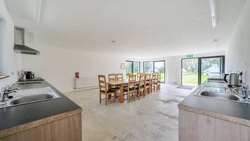 A modern kitchen with a central island, wooden chairs, and a large window providing a view of the outdoors.