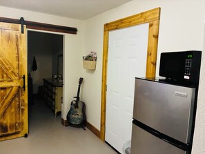 Eine Küche mit Kühlschrank, Mikrowelle und einer an der Wand angelehnten Gitarre.