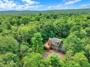 A house surrounded by dense forest with a clear sky. - Pocono Cabin Retreat | Hot Tub |Firepit |Game Room (Lake Harmony)