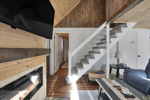 Ein modernes Wohnzimmer mit Kamin, einer Treppe und einem Sofa.