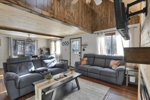 Ein geräumiges Wohnzimmer mit einem großen grauen Sofa, einem Couchtisch und einem Kamin.
