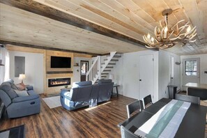 Ein geräumiges Wohnzimmer mit Kamin, einer Treppe und einem Essbereich.