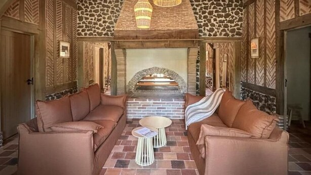 A spacious room with a stone fireplace, leather sofas, and a hanging light fixture. - La Landaise - COMMENSACQ (COMMENSACQ)
