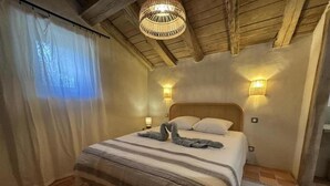 A bedroom with a bed, a woven ceiling light, wall sconces, and a window with curtains. - La Landaise - COMMENSACQ (COMMENSACQ)