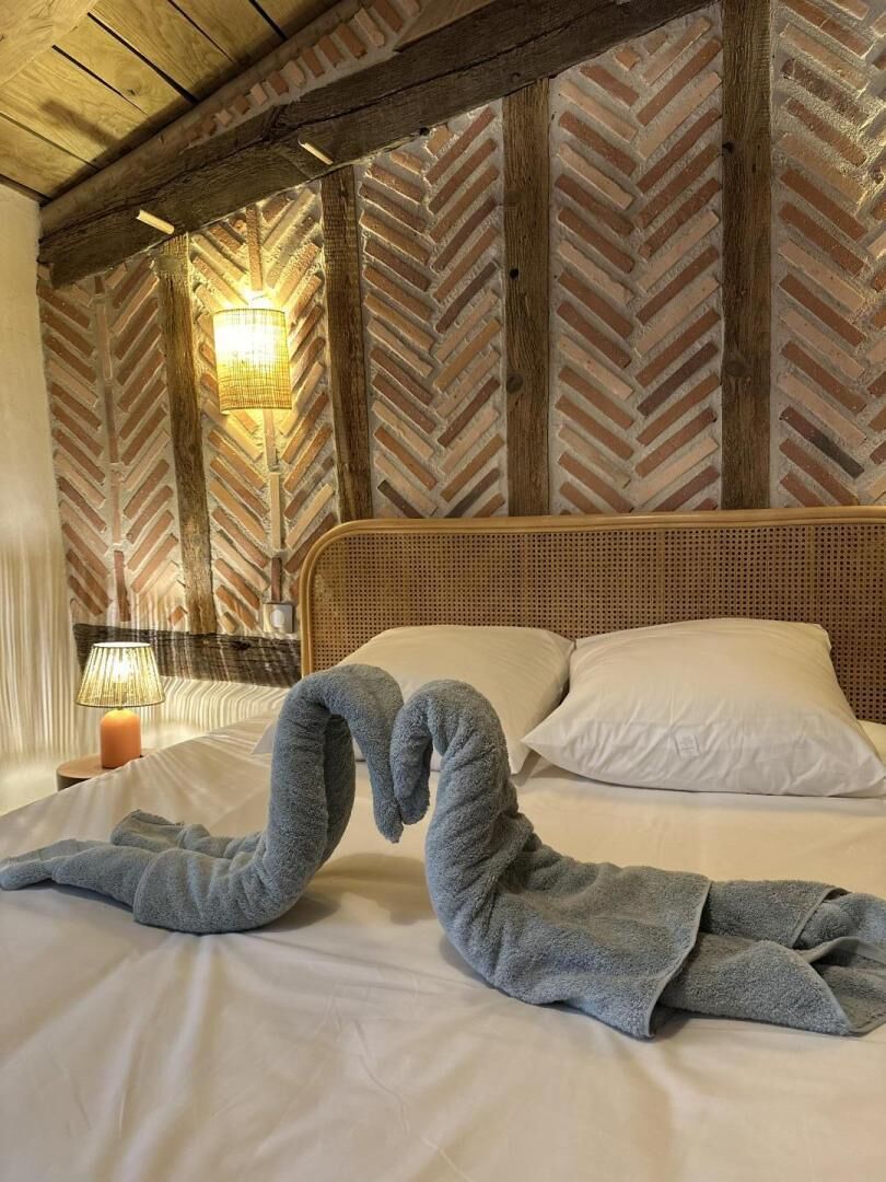 Ein Bett mit Holz-Kopfteil, eine Lampe auf einem Nachttisch und eine Wand mit Fischgrätmuster.