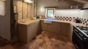 A kitchen with a herringbone-patterned wall, a window, a sink, a stove, and a microwave. - La Landaise - COMMENSACQ (COMMENSACQ)