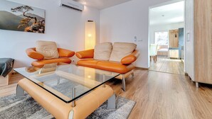 A modern living room with a glass coffee table, orange leather sofa, and a painting on the wall. - Apartament nr 32 by Interhome (Gliwice)