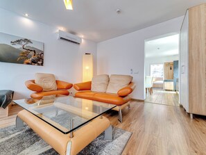 A modern living room with a glass coffee table, orange leather sofa, and a painting on the wall. - Apartament nr 32 by Interhome (Gliwice)
