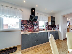 A modern kitchen with dark cabinets, a large island, and a view of the city. - Apartament nr 32 by Interhome (Gliwice)