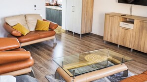 A modern living room with a leather sofa, a glass coffee table, and a wooden cabinet. - Apartament nr 32 by Interhome (Gliwice)