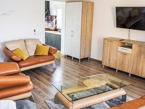 A modern living room with a leather sofa, a glass coffee table, and a wooden cabinet. - Apartament nr 32 by Interhome (Gliwice)