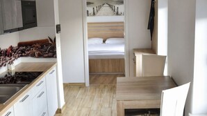 Ein modernes Zimmer mit einem Holzbett, einer Küche mit Spüle und einem Essbereich.