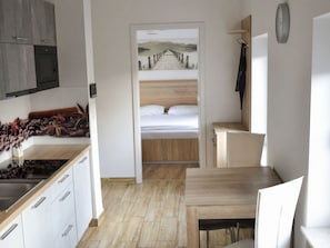 Ein modernes Zimmer mit einem Holzbett, einer Küche mit Spüle und einem Essbereich.
