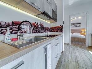 Una cocina moderna con un lavamanos de acero inoxidable, encimera de madera y un microondas empotrado.