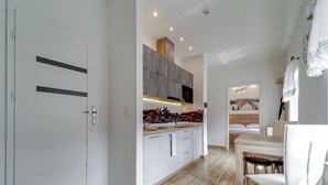 Eine moderne Küche mit Holzboden, weißen Schränken und einem Essbereich mit Tisch und Stühlen.