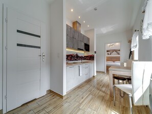 Eine moderne Küche mit Holzboden, weißen Schränken und einem Essbereich mit Tisch und Stühlen.