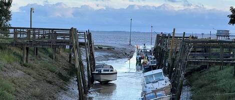 A coastal pier with boats docked, a wooden walkway, and a view of the sea.