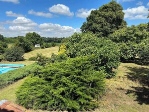 A lush garden with a swimming pool, dense greenery, and a large tree. - Farmhouse sleeps 12 - Pool, Table Tennis, Parking (St Andre de Lidon)
