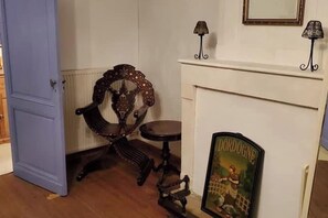 A room with a blue door, a wooden chair, a small table, a fireplace with a DORDOGNE sign, and two wall-mounted lamps. - Farmhouse sleeps 12 - Pool, Table Tennis, Parking (St Andre de Lidon)