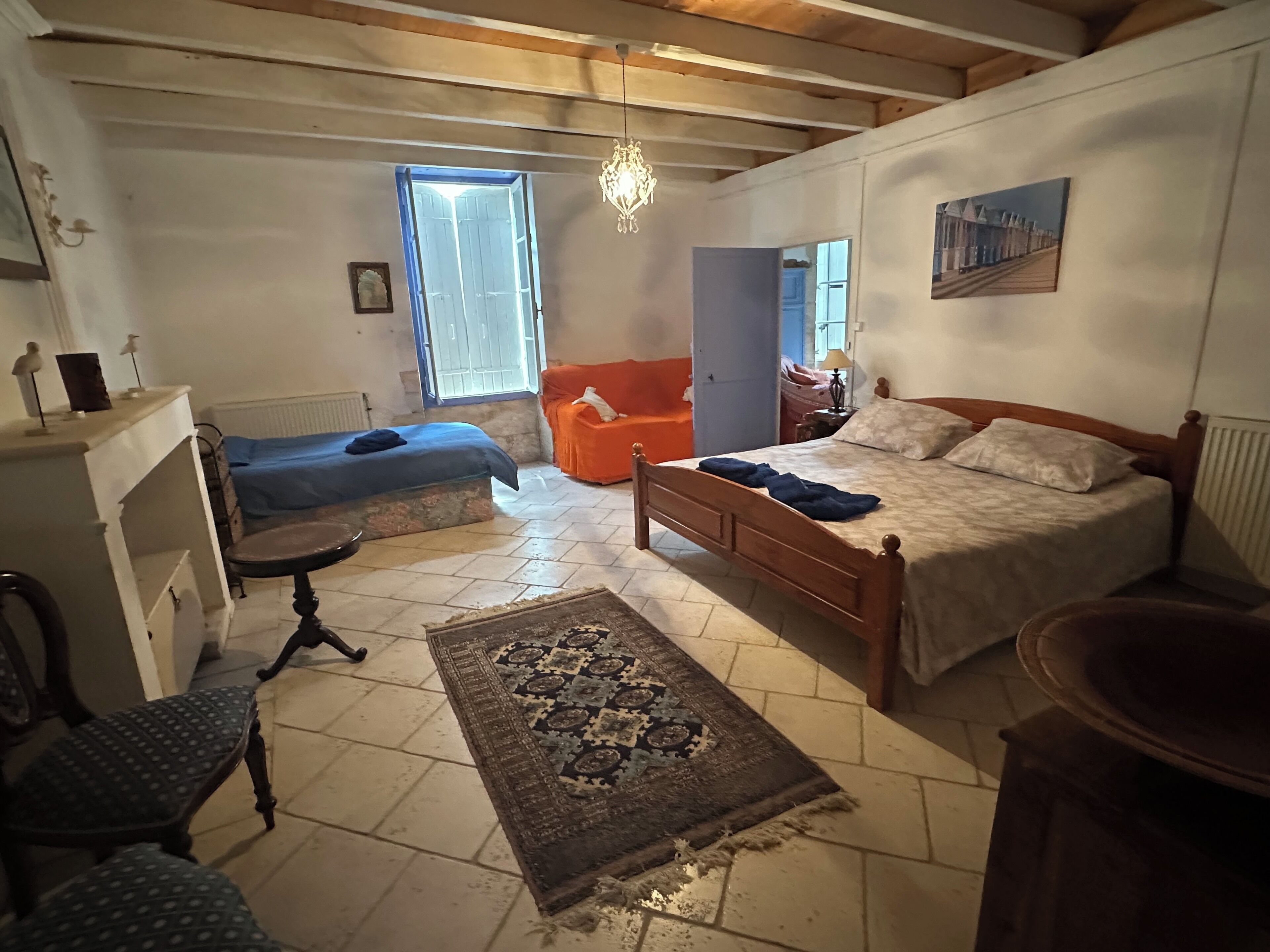 Um quarto com uma cama, uma cadeira, uma escrivaninha, um tapete e uma janela.