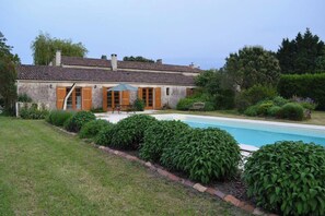 A house with a swimming pool, surrounded by well-maintained hedges and a grassy lawn. - Farmhouse sleeps 12 - Pool, Table Tennis, Parking (St Andre de Lidon)
