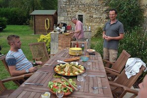 An outdoor dining area with a stone wall, wooden table, and chairs. - Farmhouse sleeps 12 - Pool, Table Tennis, Parking (St Andre de Lidon)