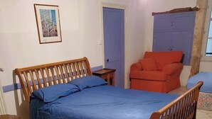 A bedroom with a wooden bed, a red chair, and a blue door. - Farmhouse sleeps 12 - Pool, Table Tennis, Parking (St Andre de Lidon)