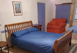 Ein Schlafzimmer mit einem hölzernen Bett, einem roten Sessel und einer blauen Tür.