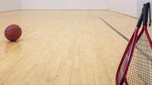 Ett rum med trägolv, en basketboll och ett tennisracket.