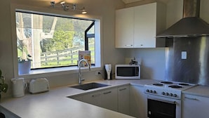 A modern kitchen with a central island, stainless steel appliances, and a window with a view of greenery.