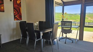 A dining area with a table and chairs, a vase with flowers, and a view of the outdoors.