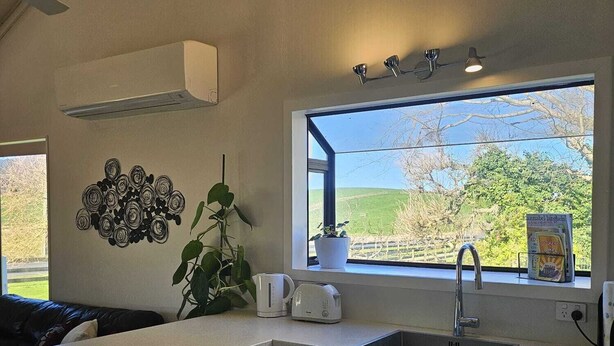 A modern kitchen with a built-in dishwasher, a sink, and a window with a view of the countryside.