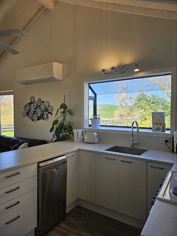 A modern kitchen with a built-in dishwasher, a sink, and a window with a view of the countryside.