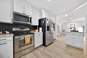 Una cocina moderna con armarios blancos, electrodomésticos de acero inoxidable y suelo de madera.